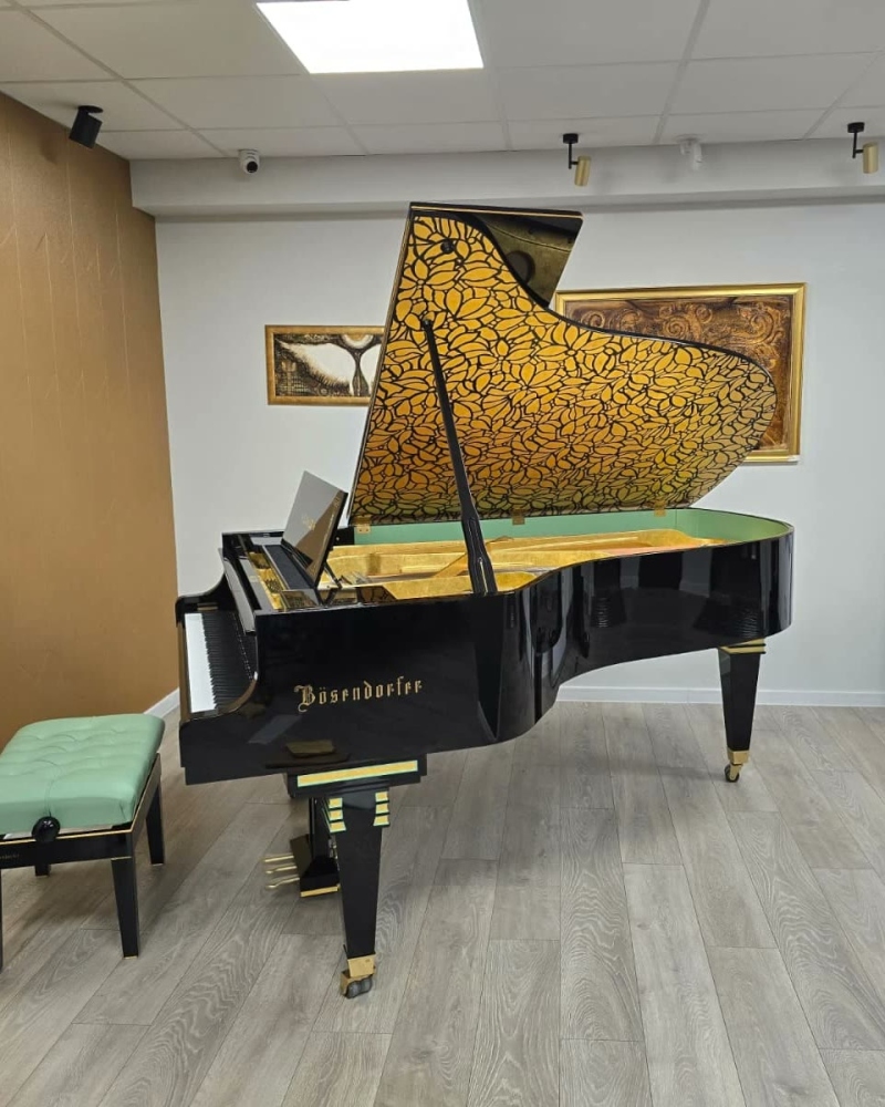 Fekete Bösendorfer zongora, a fedele belsején arany levélmintákkal, egy teremben felállítva