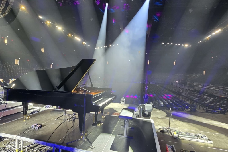 Bösendorfer hangversenyzongora egy nagy aréna színpadán, reflektorfényben